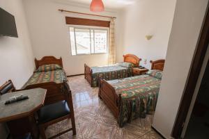 a room with three beds and a desk and a window at Hotel Fnidaq in Fnidek