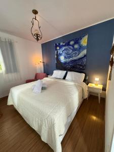 a bedroom with a large bed with a painting on the wall at Casa na "Villa Grega" pertinho do Parque Nacional, Feirinha do Alto e Granja Comary in Teresópolis +38 photos