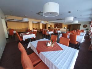 a restaurant with white tables and orange chairs at Hotel Madona in Madona