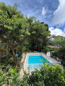 a swimming pool next to some trees at Casa na "Villa Grega" pertinho do Parque Nacional, Feirinha do Alto e Granja Comary in Teresópolis