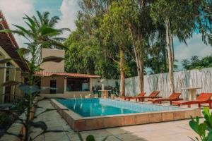 a swimming pool with orange chairs next to a house at Pousada EcoVillage - Meu Xodó em Preá in Prea
