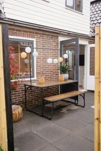 a table with a mirror and a bench in front of a building at Duijnparadijs appartement 2 in Schoorl