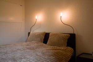 a bedroom with two lights on the wall and a bed at Huisje Weltevree Gendt in Gendt