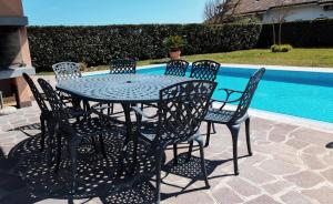 a black table and chairs next to a pool at Villa Helena, Venetien, Exklusive Villa auf Privatinsel Albarella, 4 Bedrooms 8 Personen, 300 m Strand in Isola Albarella