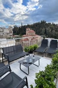 a patio with three chairs and a table on a roof at KK Athens Fine Stay -Neos Kosmos-Modern Apartments Opposite Metro with Rooftop Lounge & Acropolis Views in Athens