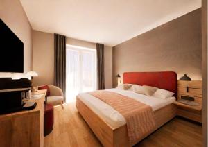 a bedroom with a large bed and a television at Hotel Adler Äpfingen in Äpfingen