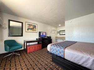 a hotel room with a bed and a desk and a chair at Budget Inn Ada in Ada