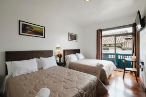 a hotel room with two beds and a window at Hostal & Apartments El Triunfo in Cusco