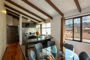 a kitchen and dining room with a glass table and chairs at Hostal & Apartments El Triunfo in Cusco