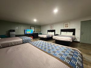 a room with three beds and a flat screen tv at Budget Inn Ada in Ada
