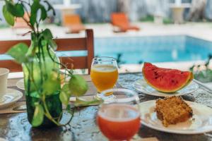 a table with two glasses of juice and a slice of watermelon at Pousada EcoVillage - Meu Xodó em Preá in Prea