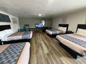 a hotel room with three beds and a flat screen tv at Budget Inn Ada in Ada