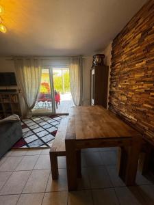 a room with a wooden table and a brick wall at Charmant pied à terre entre lac et montagne in Bourdeau