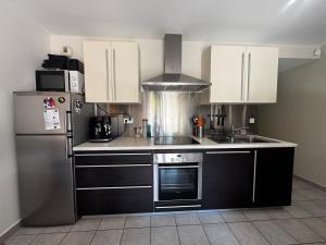 a kitchen with white cabinets and a stainless steel refrigerator at Charmant pied à terre entre lac et montagne in Bourdeau