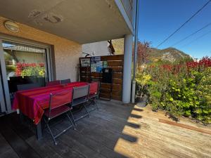 a patio with a table and chairs on a deck at Charmant pied à terre entre lac et montagne in Bourdeau