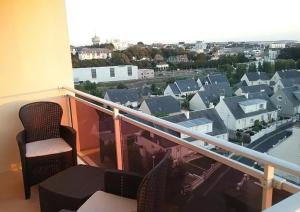 a balcony with chairs and a view of a city at La chouette verte in Granville