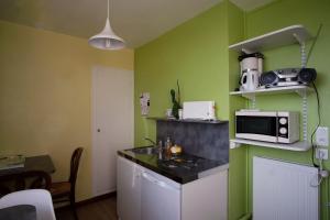 a kitchen with green walls and a counter with a microwave at La chouette verte in Granville
