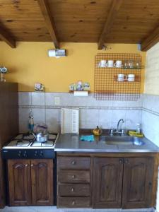 a kitchen with a sink and a stove at Cabañas Wencesmar in Hipólito Yrigoyen +9 photos