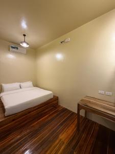 a bedroom with a white bed and a wooden floor at 9 Keys Inn in San Vicente