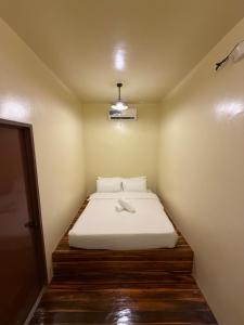 a small bedroom with a bed with a white blanket at 9 Keys Inn in San Vicente