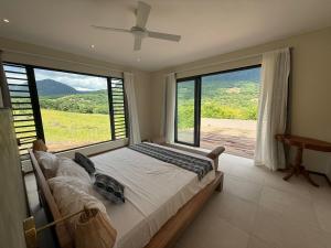 a bedroom with a bed with a large window at Casa Palmyre in Rivière Noire +11 photos