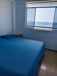 a bedroom with a blue bed and a large window at OOK Home in Canoas de Punta Sal