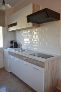 a kitchen with white cabinets and a sink at Athina studios in Ipsos
