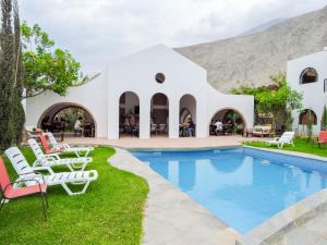 a resort with a pool with chairs and tables at Casa Hotel Mamaluna in Lunahuaná
