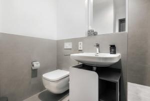 a bathroom with a sink and a toilet and a mirror at Oskar25 Aparthotel in Ismaning