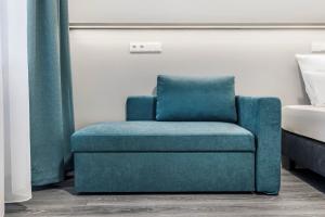 a blue chair sitting in a room next to a bed at Oskar25 Aparthotel in Ismaning