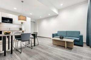 a living room with a blue couch and a table at Oskar25 Aparthotel in Ismaning +8 photos