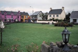 a group of houses in a yard with a green lawn at Grace's Landing in Sneem