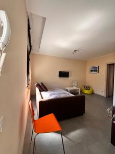 a bedroom with a bed and a orange chair at El Jardin in Bellano