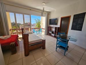 a bedroom with a bed and a table and a balcony at Apartamentos Casa da Pedra in Ubatuba