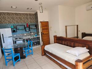 a bedroom with a bed and a table and a refrigerator at Apartamentos Casa da Pedra in Ubatuba