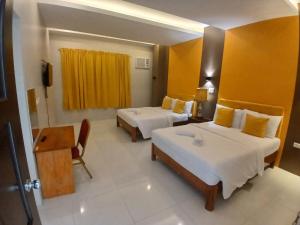 a hotel room with two beds and a television at Maison De Gloria in Locsin