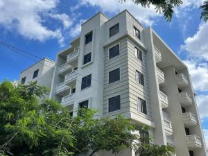 a white apartment building with trees in the foreground at High Tide BnB Apartment in Mombasa