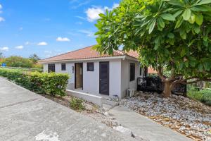 a small white house with a tree and a sidewalk at Luxury Villas with Panoramic View in Blue Bay in Blue Bay