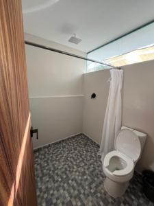 a bathroom with a toilet with a shower curtain at Hotel Mare in Santa Maria Huatulco