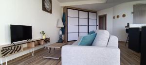 a living room with a white couch and a television at Appartement face golf et océan in Saint-Jean-de-Monts