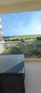 a balcony with a bench in front of a large window at Appartement face golf et océan in Saint-Jean-de-Monts