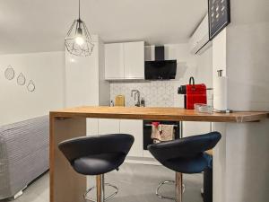 a kitchen with a bar with two black stools at Le Refuge in Valence +1 photo