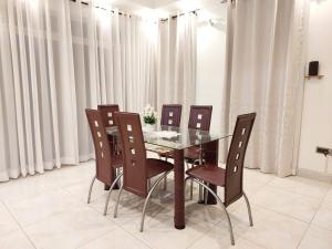 a dining room with a glass table and chairs at Laxury3BR Mins to Nyali Beach fast WiFi Netflix AC and Free Parking Near wild waters in Mombasa +7 photos