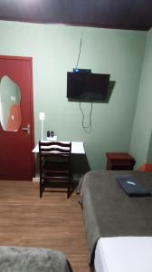 a room with two beds and a desk and a tv at Hotel Real Paulista in São Paulo