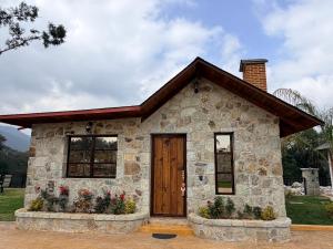 a small stone house with flowers in front of it at Royal Fest By GEstores in Huasca de Ocampo