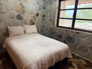a bed in a room with a stone wall at Royal Fest By GEstores in Huasca de Ocampo
