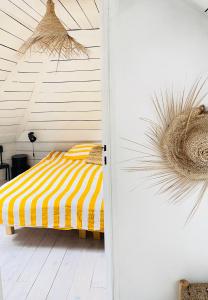 a bedroom with a bed with a yellow and white stripes at White and Sea Lodge in Locquirec