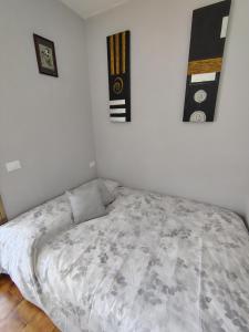 a bed in a bedroom with two pictures on the wall at "Le Betulle 10" cinque minuti dal mare, Self check in in Bibione