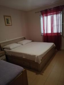 a bedroom with two beds and a window with red curtains at Apartment Pavin in Poljana