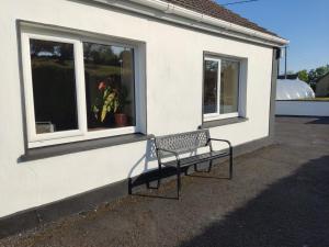 a bench sitting outside of a building with two windows at Woodmount Cottage in Ennistymon